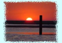 Het strand in Ouddorp met de ondergaande zon